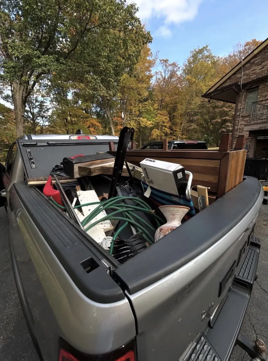 Pickup truck bed loaded with a dresser, hoses and household junk